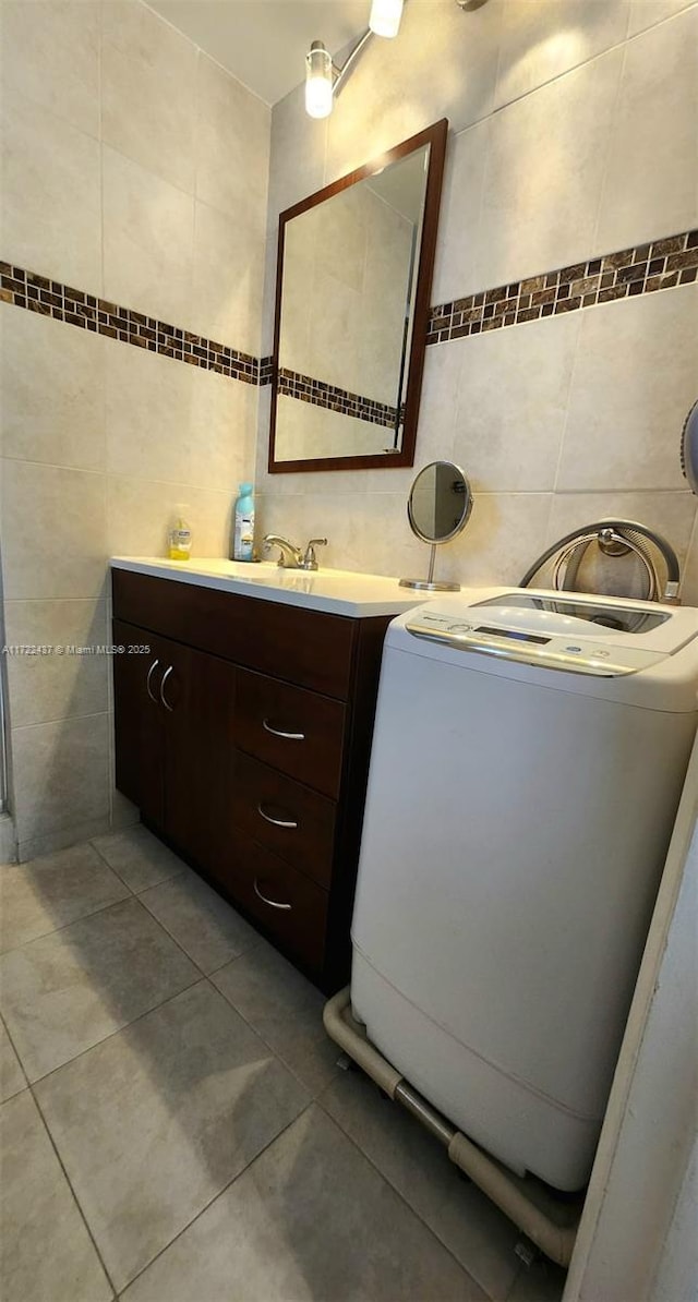 bathroom with tile walls, washer / dryer, vanity, and tile patterned flooring