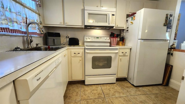 kitchen with white appliances, white cabinets, light tile patterned flooring, and sink