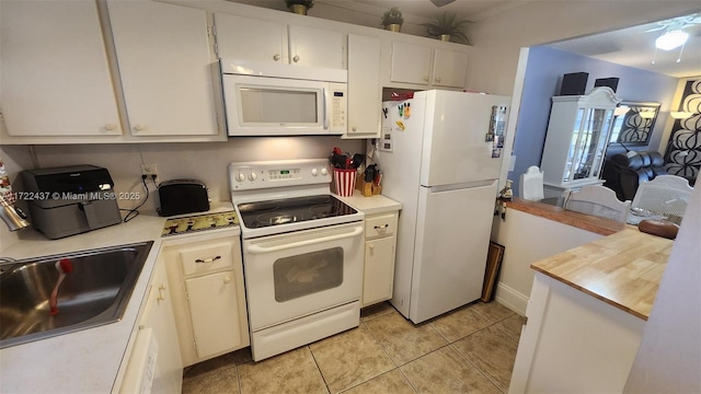 kitchen featuring white appliances, white cabinets, sink, and light tile patterned floors