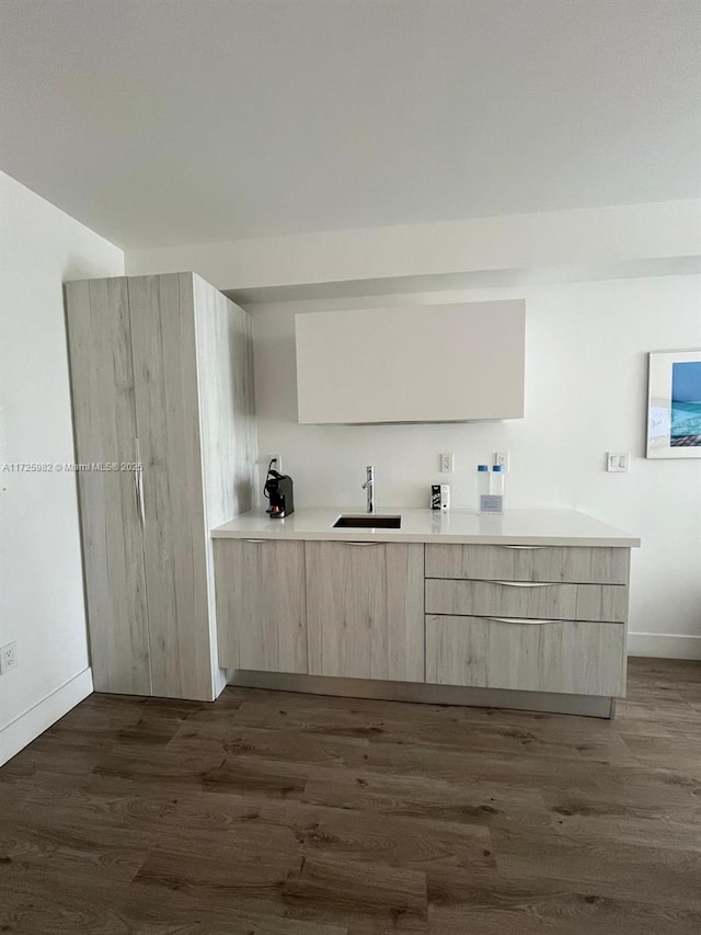 kitchen featuring kitchen peninsula, light brown cabinetry, dark hardwood / wood-style flooring, and sink