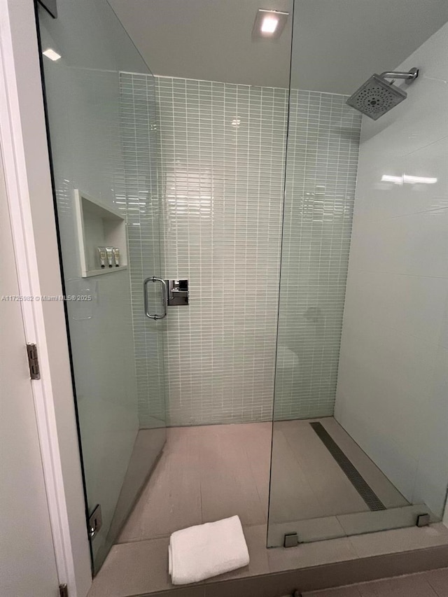 bathroom featuring a shower with shower door and tile patterned flooring