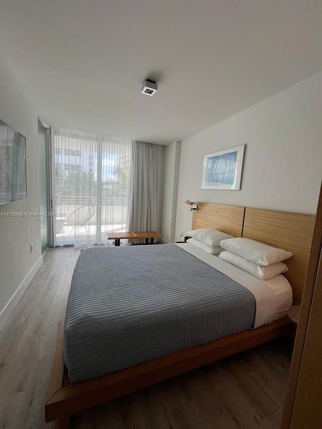 bedroom featuring hardwood / wood-style floors and a wall of windows