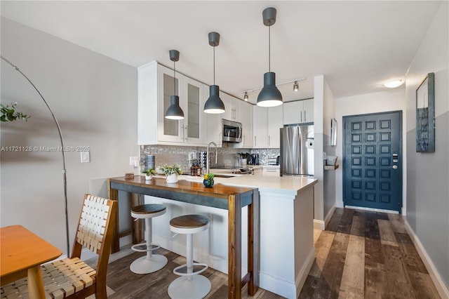 kitchen featuring stainless steel appliances, hanging light fixtures, kitchen peninsula, white cabinets, and butcher block counters