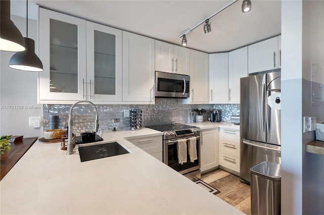 kitchen with pendant lighting, backsplash, white cabinetry, appliances with stainless steel finishes, and sink