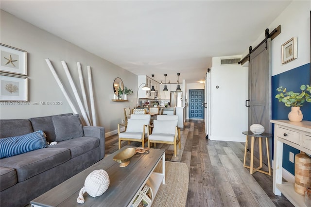 living room with a barn door and dark wood-type flooring