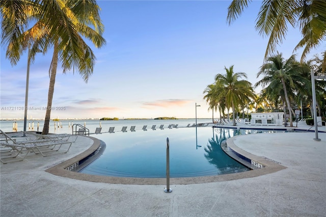 pool at dusk featuring a water view