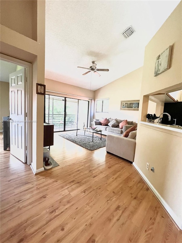 living room featuring hardwood / wood-style flooring, a textured ceiling, ceiling fan, and vaulted ceiling