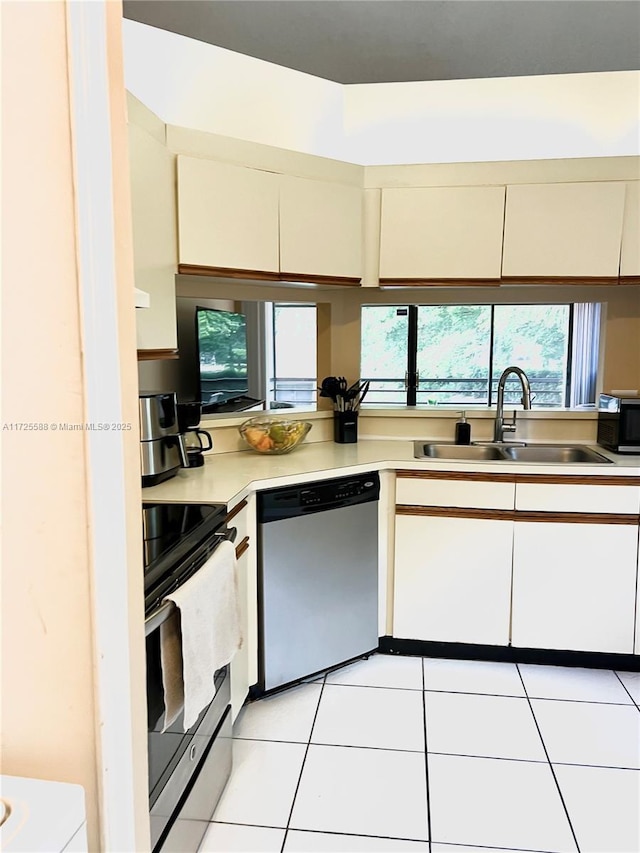 kitchen featuring appliances with stainless steel finishes, white cabinetry, light tile patterned floors, and sink