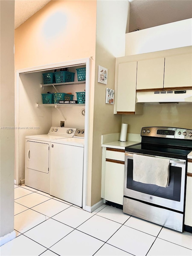 kitchen with independent washer and dryer, light tile patterned flooring, white cabinets, and stainless steel range with electric stovetop