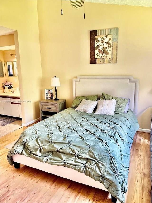 bedroom with sink, ensuite bath, and hardwood / wood-style floors