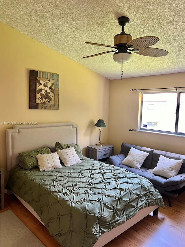 bedroom with ceiling fan, a textured ceiling, and wood-type flooring