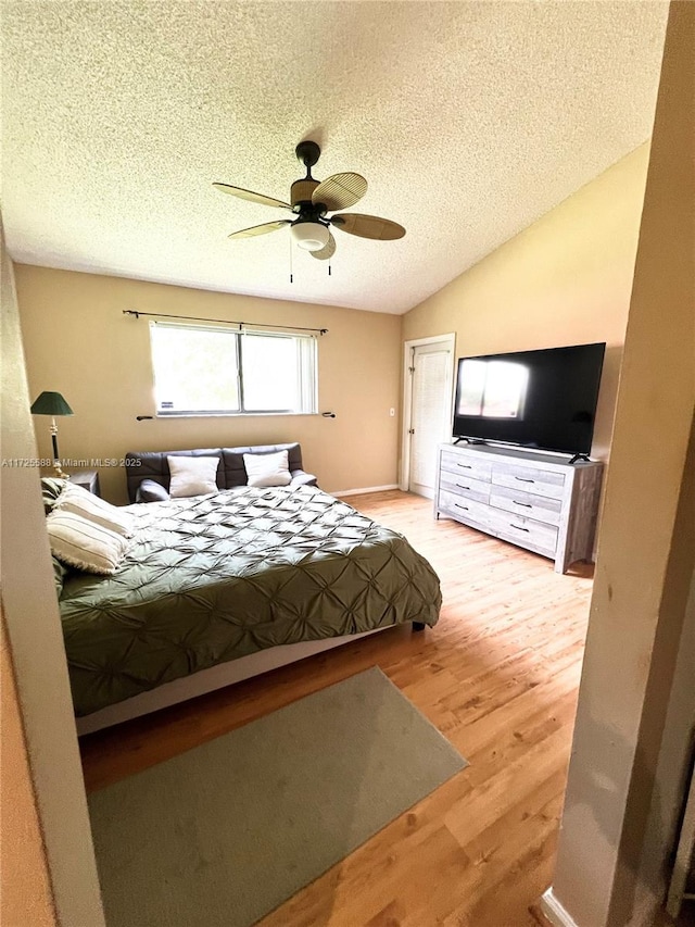 bedroom with ceiling fan, light wood-type flooring, lofted ceiling, and a textured ceiling