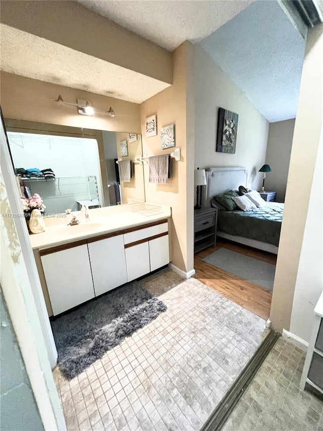 10 Via De Casas Sur Unit 205, Boynton Beach, FL 33426 - bathroom featuring lofted ceiling, connected bathroom, vanity, and a textured ceiling