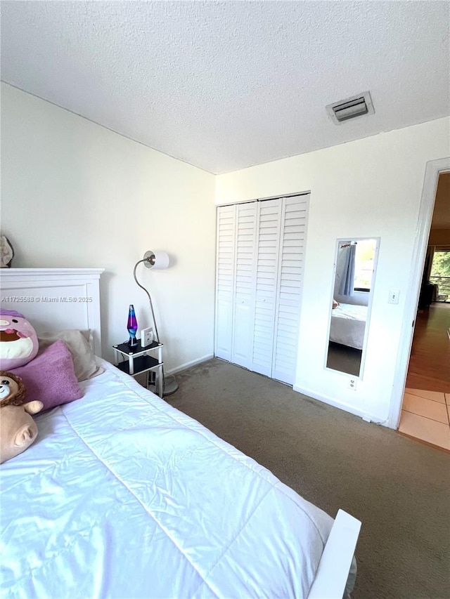 carpeted bedroom with a textured ceiling and a closet