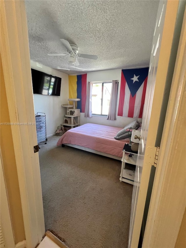 bedroom featuring carpet flooring, a textured ceiling, and ceiling fan