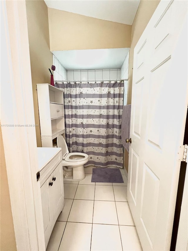 bathroom featuring curtained shower, tile patterned floors, vanity, and toilet