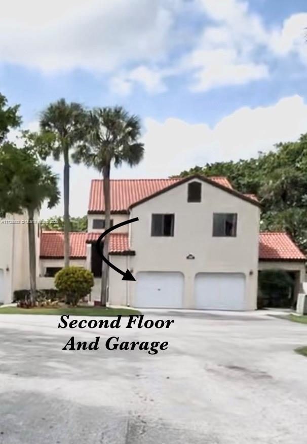 10 Via De Casas Sur Unit 205, Boynton Beach, FL 33426 - exterior space featuring a garage, driveway, stucco siding, and a tile roof