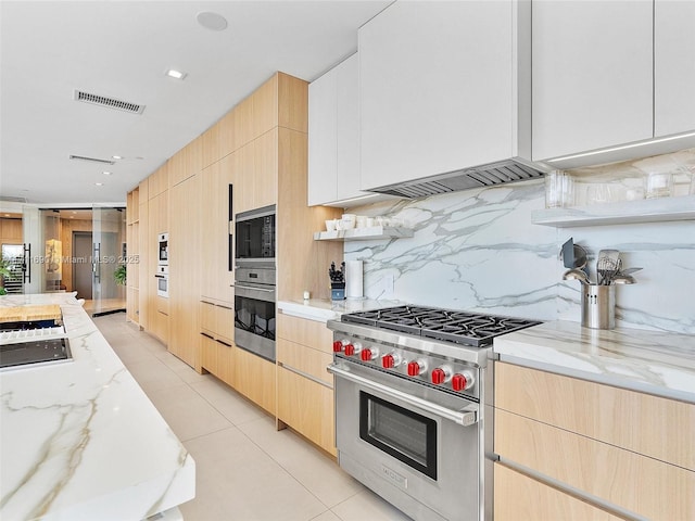 kitchen with light stone countertops, light tile patterned floors, decorative backsplash, designer stove, and light brown cabinets