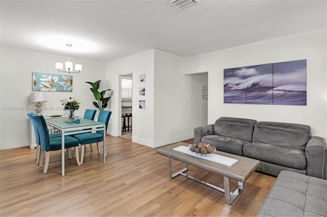 living room featuring ornamental molding, light hardwood / wood-style floors, and an inviting chandelier