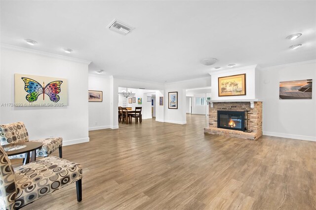 living room with crown molding, wood-type flooring, a notable chandelier, and a fireplace