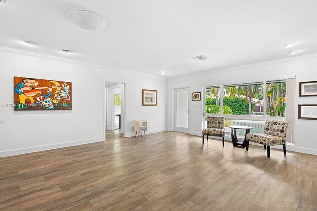 living area featuring hardwood / wood-style flooring and crown molding