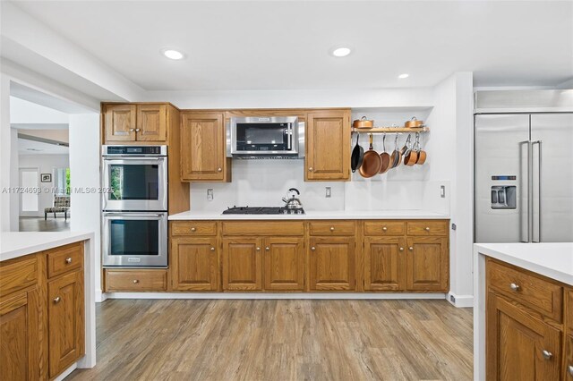 kitchen with appliances with stainless steel finishes and light hardwood / wood-style floors