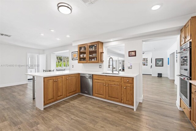 kitchen featuring wood-type flooring, appliances with stainless steel finishes, sink, and kitchen peninsula