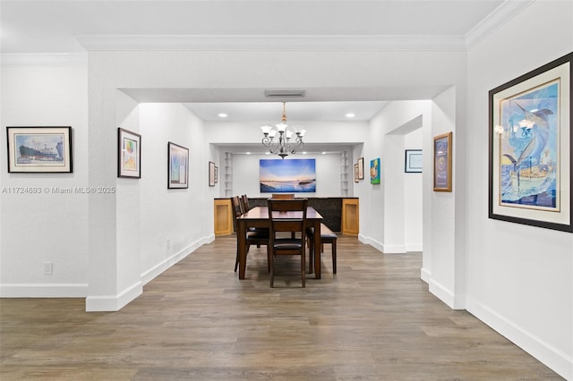 dining room with crown molding, wood-type flooring, and an inviting chandelier