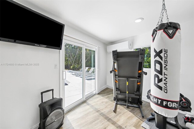 workout area with light wood-type flooring and a wall unit AC