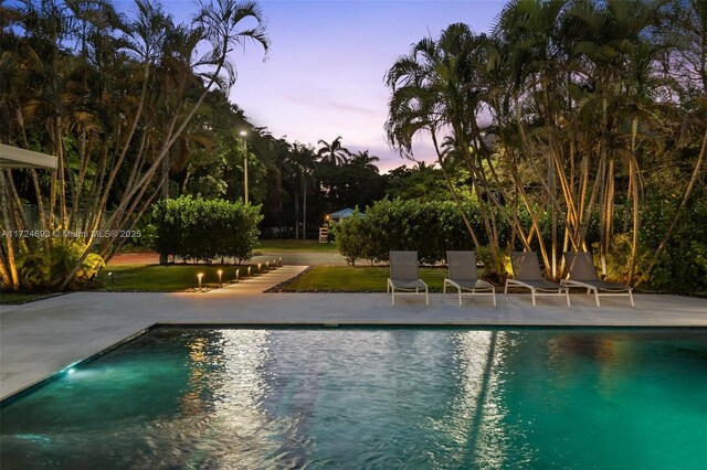 pool at dusk featuring a patio