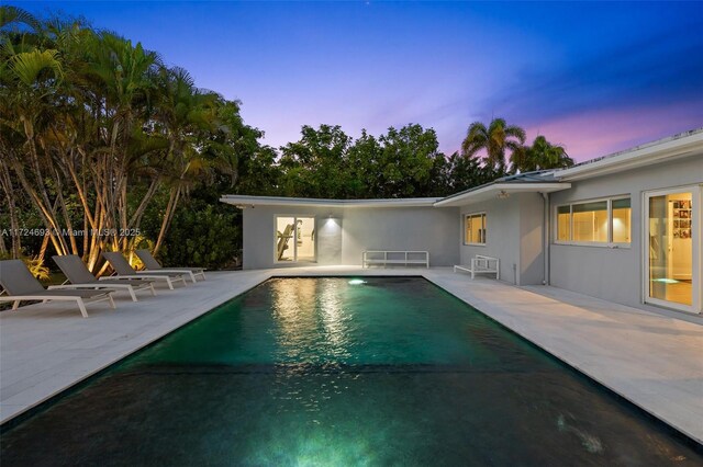 pool at dusk featuring a patio