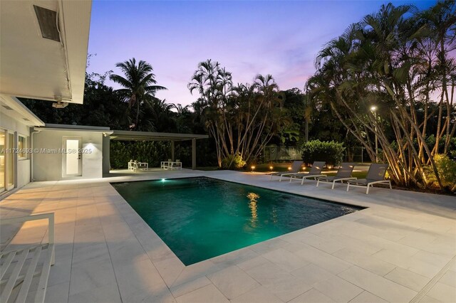 pool at dusk featuring a patio