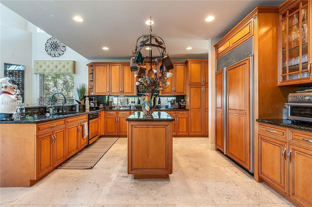 kitchen featuring paneled built in refrigerator, dark stone counters, a kitchen island, sink, and tasteful backsplash