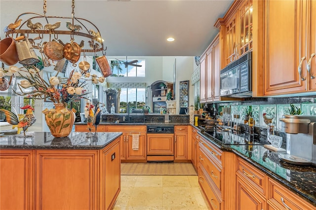 kitchen with black appliances, dark stone counters, and kitchen peninsula