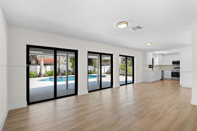 unfurnished living room with light wood-type flooring and sink