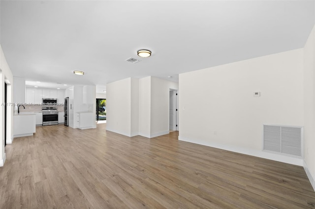 unfurnished living room featuring sink and light wood-type flooring