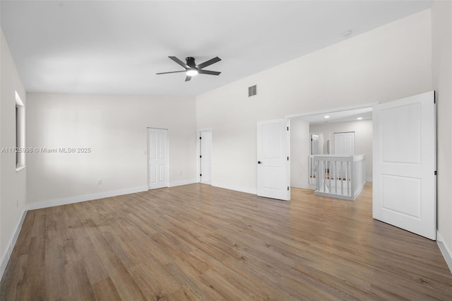 interior space with ceiling fan, a towering ceiling, and hardwood / wood-style floors