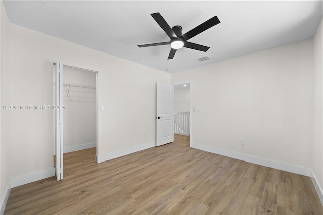 unfurnished bedroom featuring ceiling fan, a closet, a spacious closet, and light hardwood / wood-style flooring