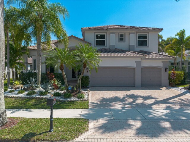 mediterranean / spanish home featuring a garage, driveway, a tiled roof, and stucco siding