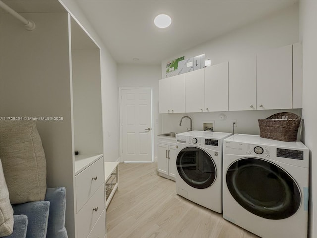 laundry room featuring light wood-type flooring, cabinet space, independent washer and dryer, and a sink