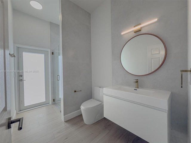 bathroom featuring toilet, a stall shower, wood finished floors, and vanity