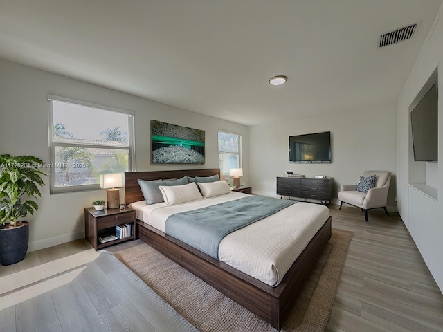 bedroom featuring wood finished floors, visible vents, and baseboards