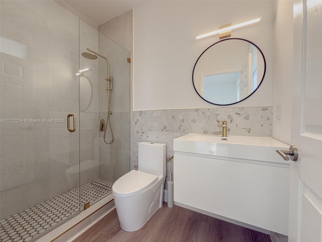 full bath featuring toilet, wood finished floors, vanity, tile walls, and a stall shower