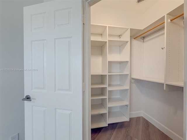 walk in closet with dark wood-style floors