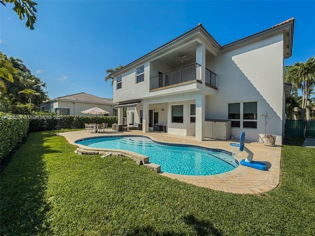 back of property featuring a ceiling fan, a balcony, a fenced backyard, a yard, and a patio area