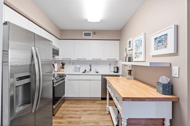 kitchen with stainless steel appliances, white cabinets, and wood counters