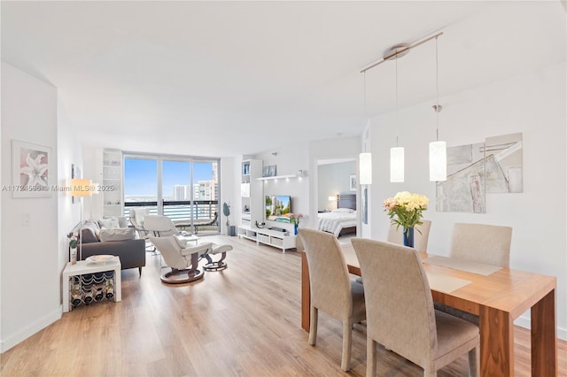 dining room with light wood-type flooring, track lighting, and expansive windows