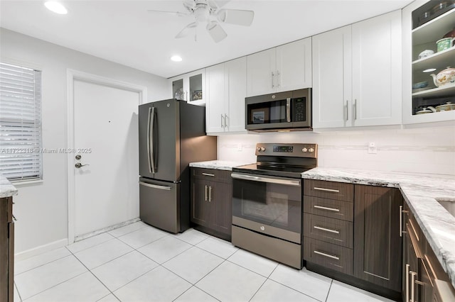 kitchen with stainless steel appliances, light stone counters, decorative backsplash, dark brown cabinetry, and white cabinets