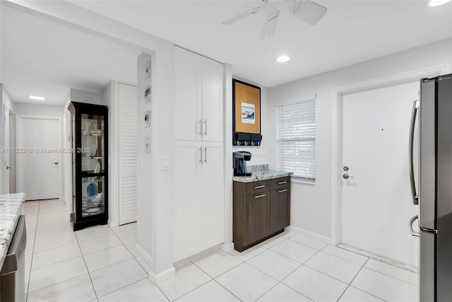 kitchen featuring stainless steel appliances, light tile patterned floors, ceiling fan, light stone counters, and white cabinets