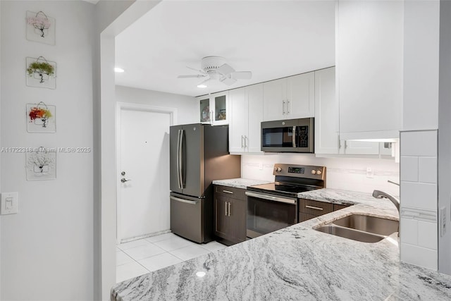 kitchen with light stone counters, white cabinets, appliances with stainless steel finishes, ceiling fan, and sink